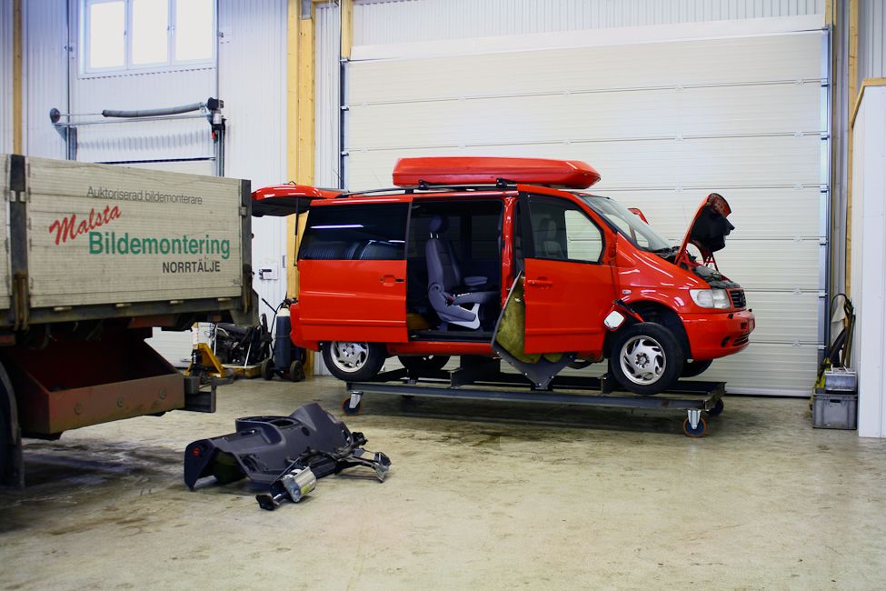 Stor bil i rött med öppen motorhuv i lagerlokal