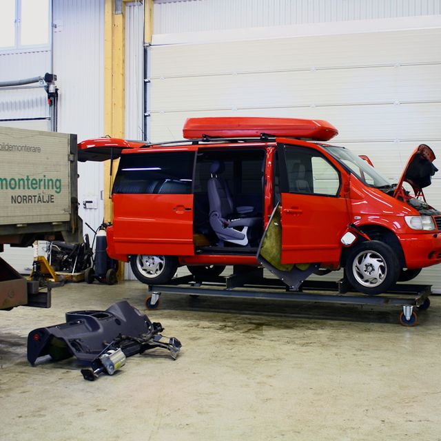 Stor bil i rött med öppen motorhuv i lagerlokal